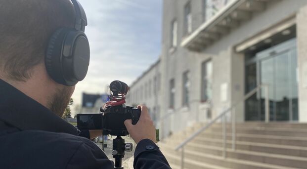 Person filmt mit einer Kamera das Rathaus