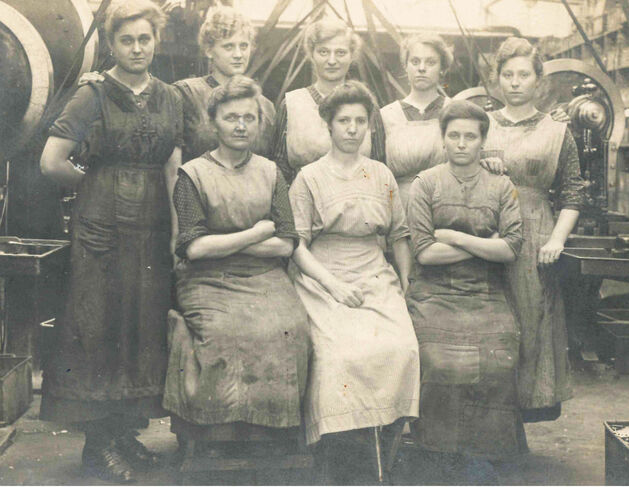 Zu sehen sind acht Frauen in der Maschinenhalle der Firma August Engels Eisenguss. Das Foto stammt aus der Zeit des 1. Weltkriegs (1914-1918), als Fauen verstärkt zur Industriearbeit herangezogen wurden.