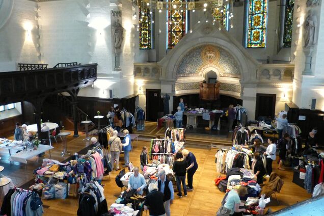 Innenaufnahme einer Kirche, Menschen begutachten Kleidung auf Verkaufsständen