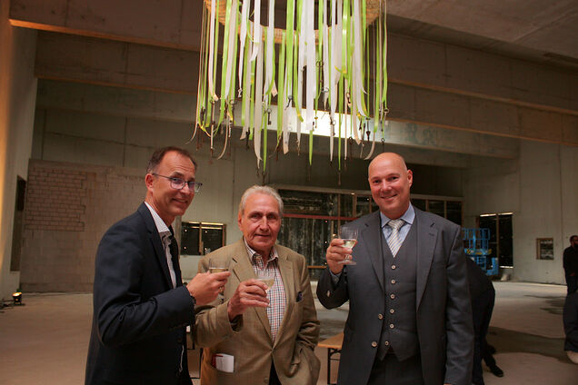 Zu sehen sind von links Manuel Villanueva-Schmidt, Heinz Schemken und Bürgermeister Dirk Lukrafka unter dem Richtkranz in der Halle des Neubaus des Deutschen Schloss- und Beschlägemuseums während des Richtfests.
